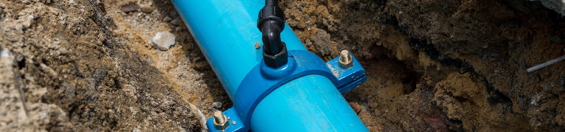 A blue plastic sewer line being repaired in the dirt outside