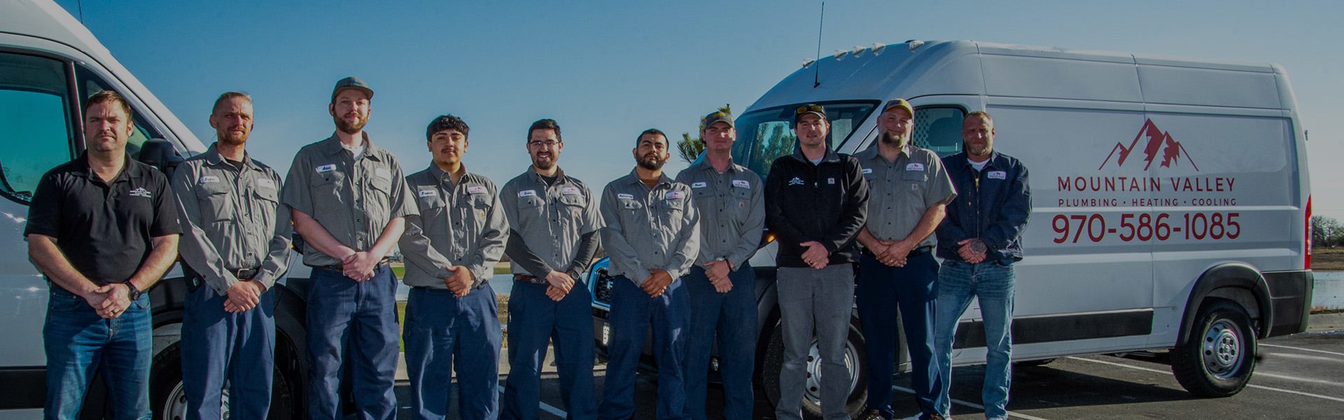 mountain valley plumbing heating and cooling staff outside standing in front of two company work vans posing.