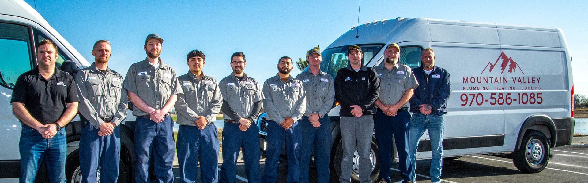 Mountain Valley Plumbing, Heating and Cooling staff in front of two work company vans.