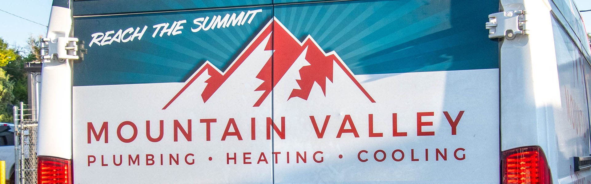 Rear view of a Mountain Valley Plumbing work van with company logo on the back of van.