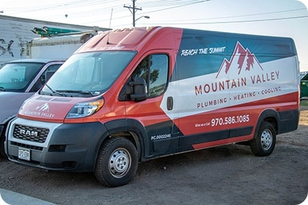 mountain valley plumbing and HVAC company red van with logo on the side parked in a lot