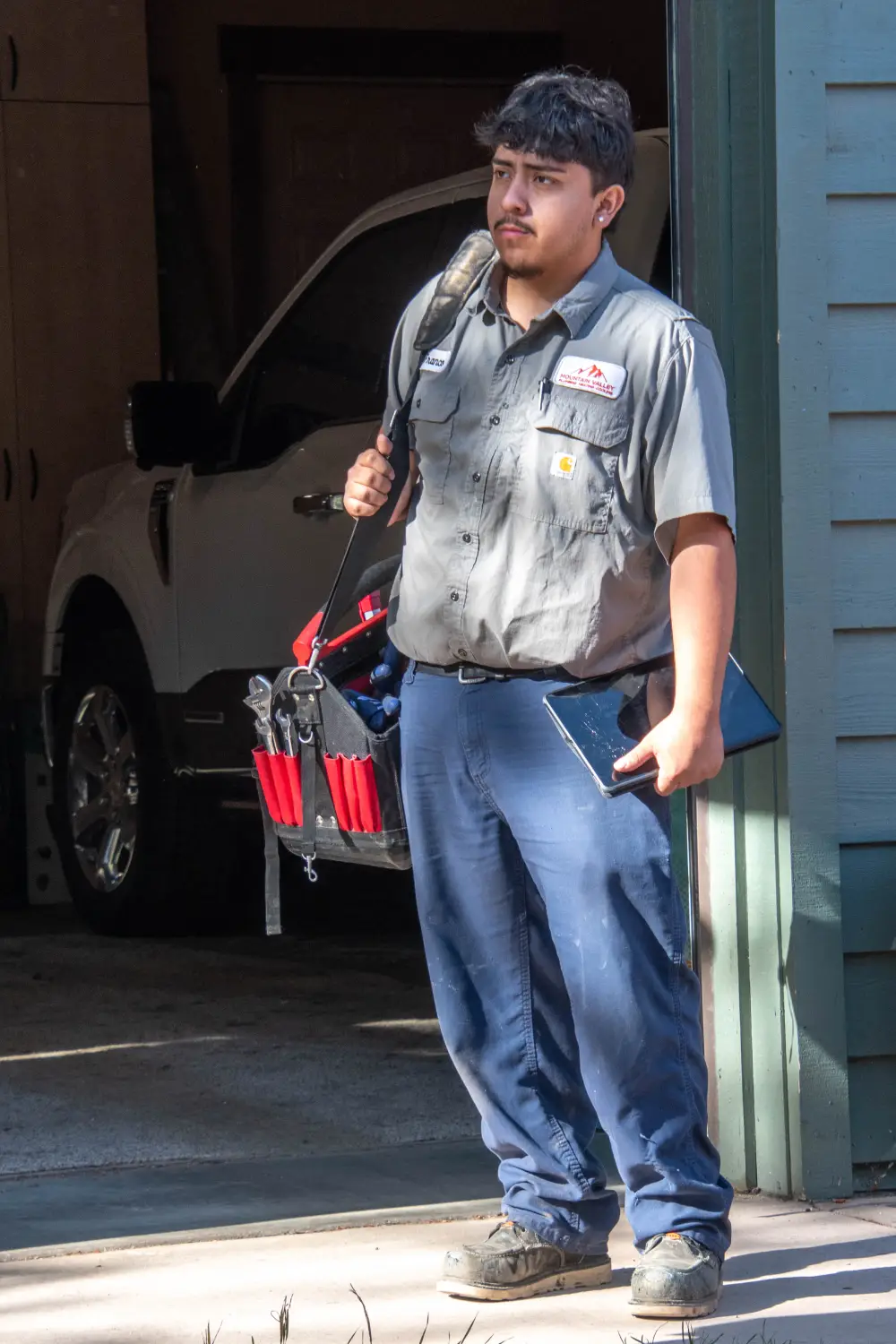 Repair technician standing near a garage with tools and tablet