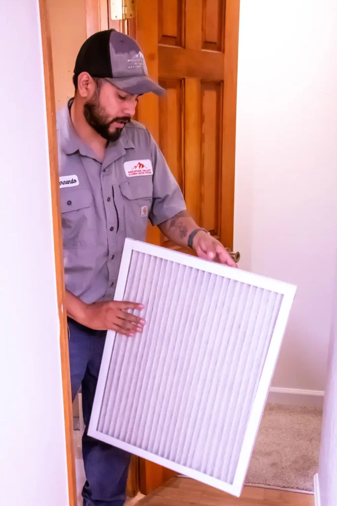Technician changing air filter in a residential home hallway