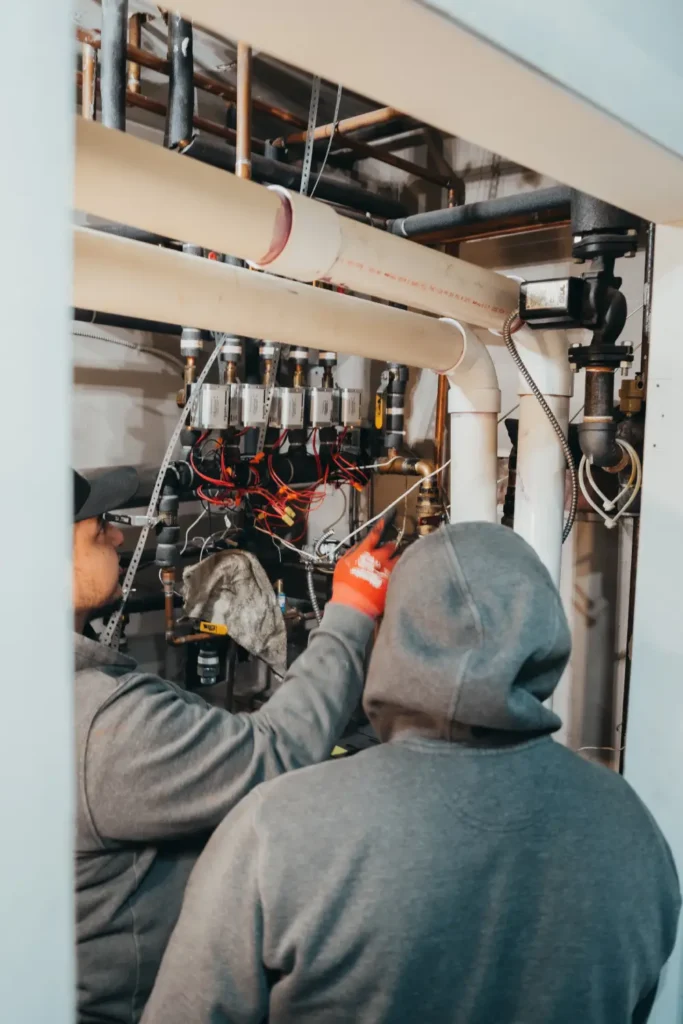 Workers inspecting commercial plumbing systems indoors