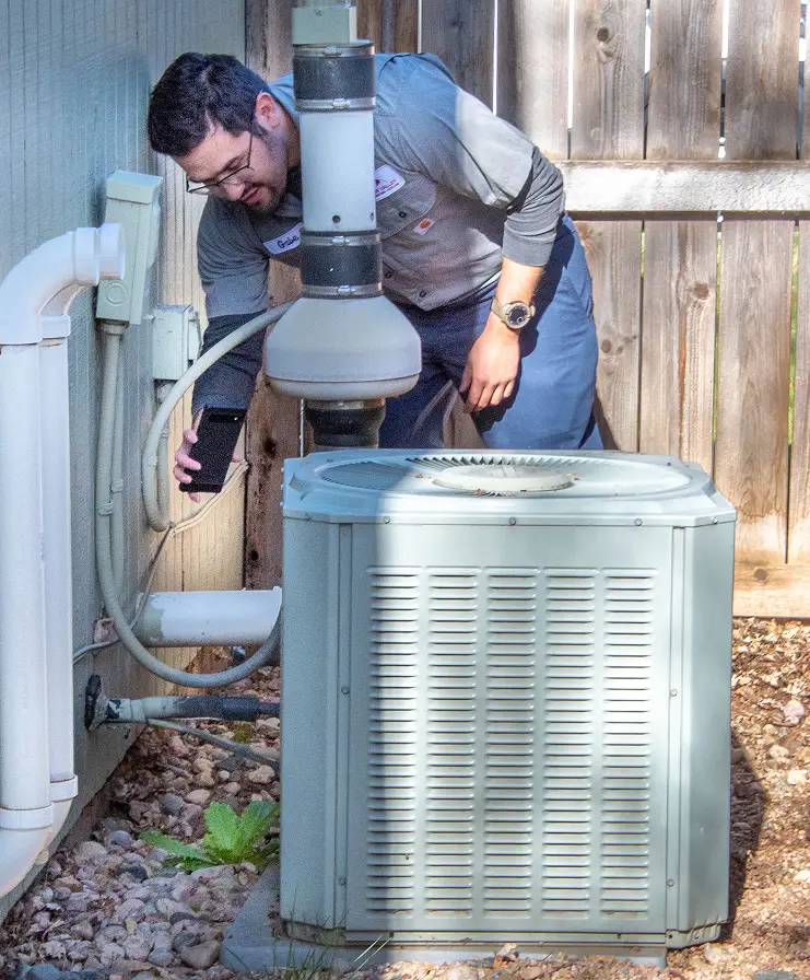 Technician inspecting outdoor air conditioning unit for maintenance
