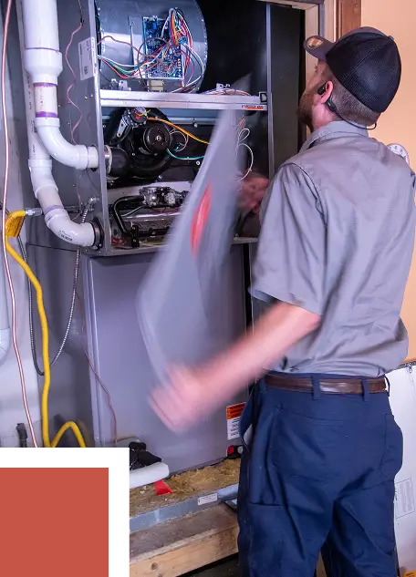 HVAC technician removing a panel to access and service the internal components of a furnace unit.